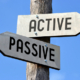Wooden signpost with two arrows and black words on them.