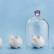Piggybank protected under a glass dome on blue background